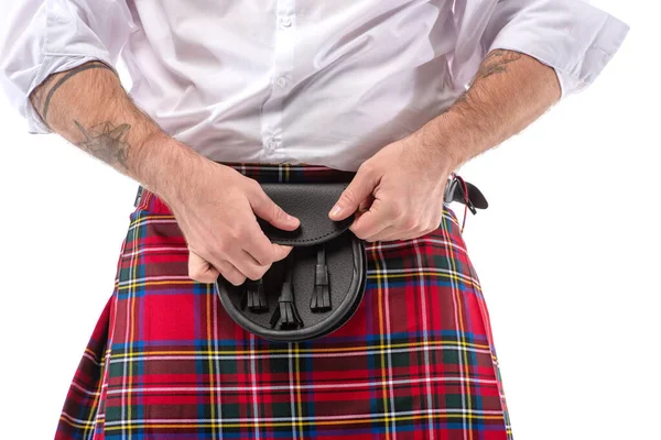 Vue recadrée de l'homme écossais en kilt rouge touchant sac de ceinture en cuir isolé sur blanc — Photo de stock