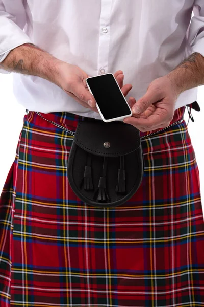 Cropped view of Scottish man in red kilt with leather belt bag and smartphone isolated on white — Stock Photo