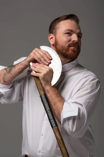 Escocês ruiva homem barbear barba com machado de batalha no fundo cinza — Fotografia de Stock