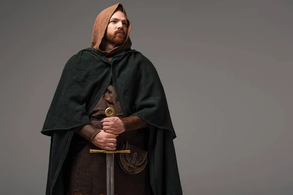 Medieval Scottish redhead knight in mantel with sword on grey background — Stock Photo