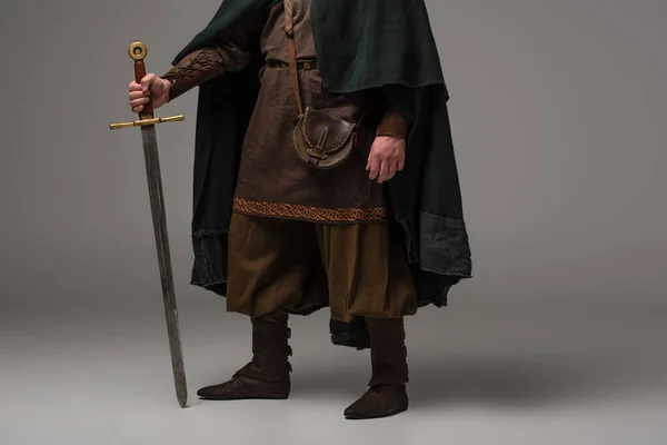 Vista recortada de caballero escocés medieval en repisa con espada sobre fondo gris - foto de stock