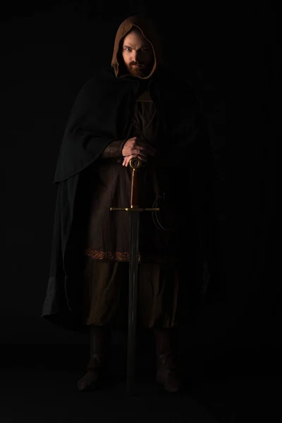 Medieval escocés hombre en mantel con espada en oscuro aislado en negro - foto de stock