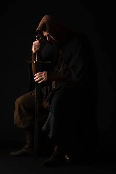 Medieval escocés hombre en mantel con espada en oscuro aislado en negro - foto de stock