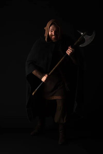 Crazy medieval Scottish warrior with battle axe in mantel isolated on black — Stock Photo