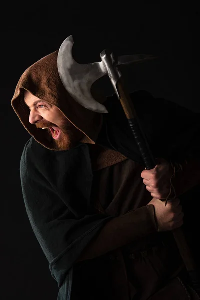 Mittelalterlicher schottischer Krieger mit Schlachtaxt im Mantel, der isoliert auf schwarz schreit — Stockfoto