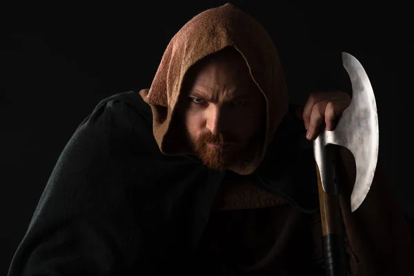 Portrait of frowning medieval Scottish warrior with battle axe in mantel isolated on black — Stock Photo