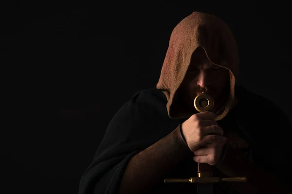 Medieval Scottish man in mantel with sword  in dark isolated on black — Stock Photo