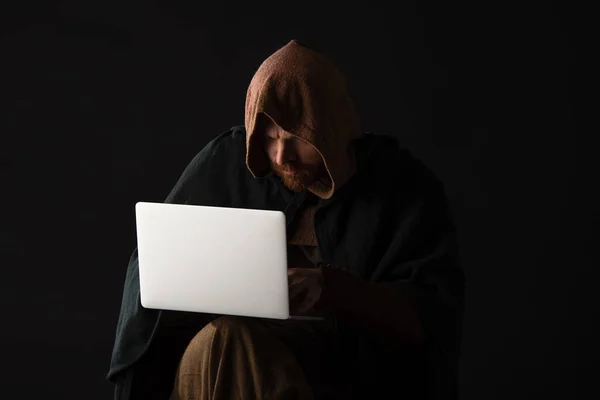 Médiéval écossais homme dans mantel en utilisant ordinateur portable dans l'obscurité isolé sur noir — Photo de stock