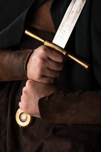 Cropped view of medieval Scottish warrior with sword in hands — Stock Photo