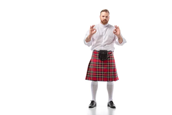 Écossais rousse barbu homme en rouge tartan kilt montrant ok gestes sur fond blanc — Photo de stock