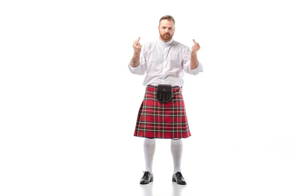 Scottish redhead bearded man in red tartan kilt showing middle fingers on white background — Stock Photo