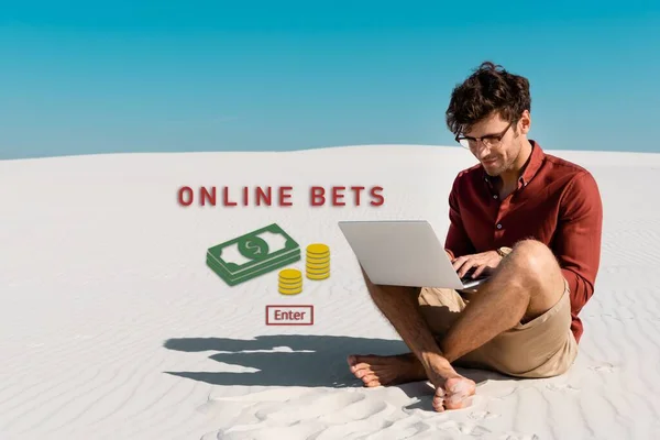 Joven freelancer en la playa de arena usando el ordenador portátil contra el cielo azul claro, ilustración de apuestas en línea - foto de stock