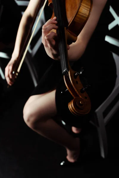 Cropped view of female musician playing on violin on dark stage — Stock Photo