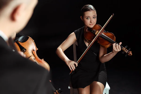 Professional female musicians playing classical music on violins on dark stage — Stock Photo