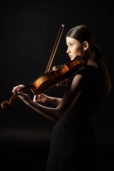 Atractiva mujer músico tocando en violín aislado en negro - foto de stock