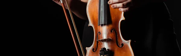Частковий погляд на професійного музиканта, який тримає скрипку ізольовано на чорній, панорамній концепції — стокове фото
