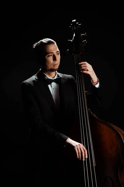 Male professional musician playing on contrabass isolated on black — Stock Photo