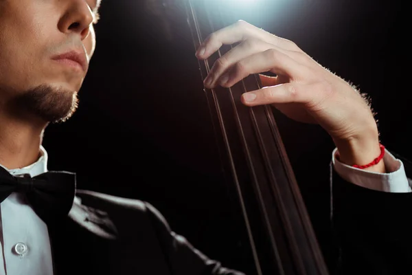 Ausgeschnittene Ansicht eines Musikers, der auf einer dunklen Bühne mit Gegenlicht auf dem Kontrabass spielt — Stockfoto