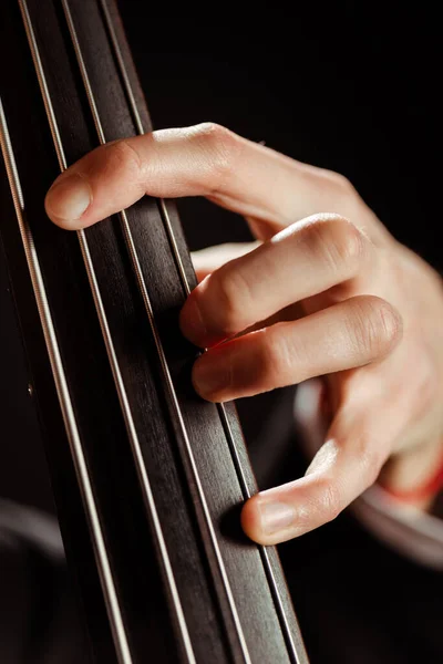 Primer plano de músico tocando en contrabajo aislado en negro - foto de stock