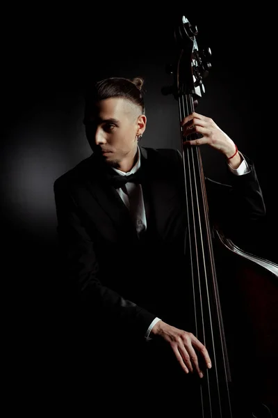 Professional musician playing on contrabass on dark stage — Stock Photo