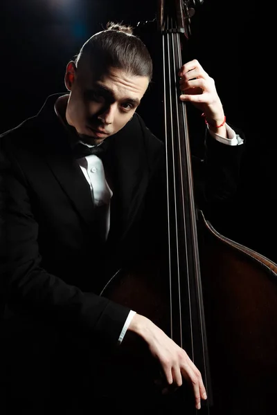 Professional musician playing on double bass on dark stage — Stock Photo