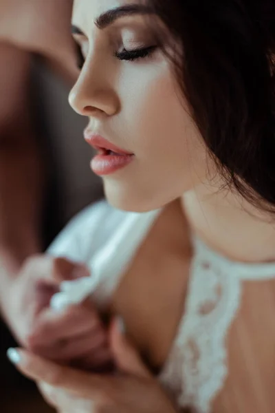 Close up view of man undressing brunette sexy woman with closed eyes — Stock Photo