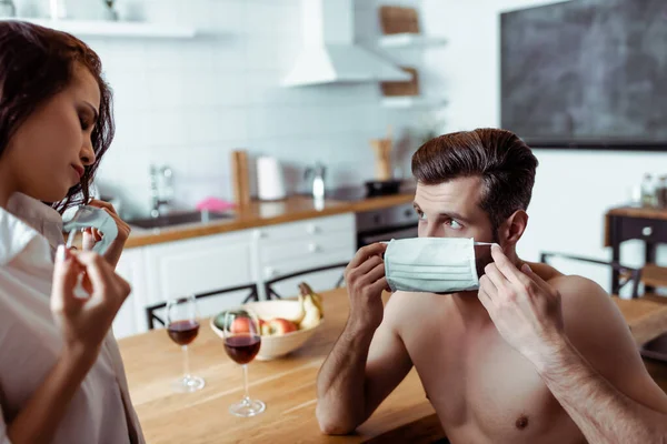 Sexy junges Paar mit medizinischen Masken in der Küche — Stockfoto