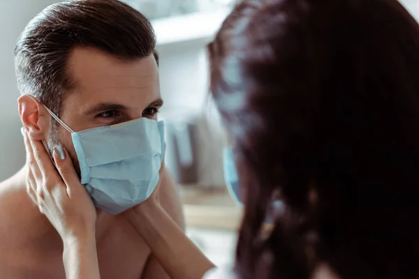 Селективное внимание женщины, касающейся сексуального молодого человека в медицинской маске — стоковое фото