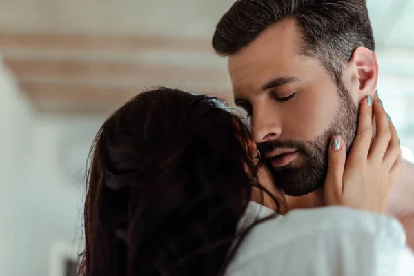 Junge brünette Frau küsst Mann mit geschlossenen Augen — Stockfoto
