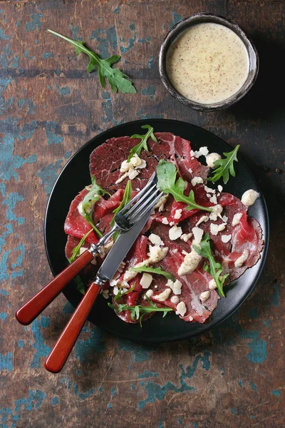 Beef carpaccio with arugula and sauce — Stock Photo, Image