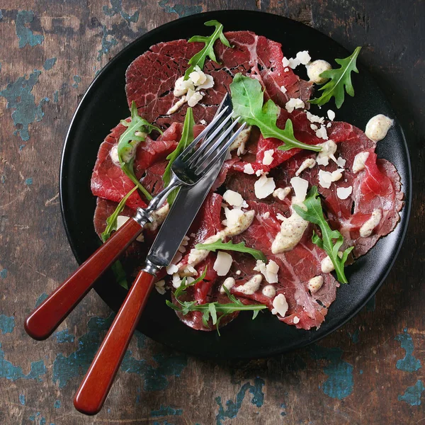 Beef carpaccio with arugula and sauce — Stock Photo, Image