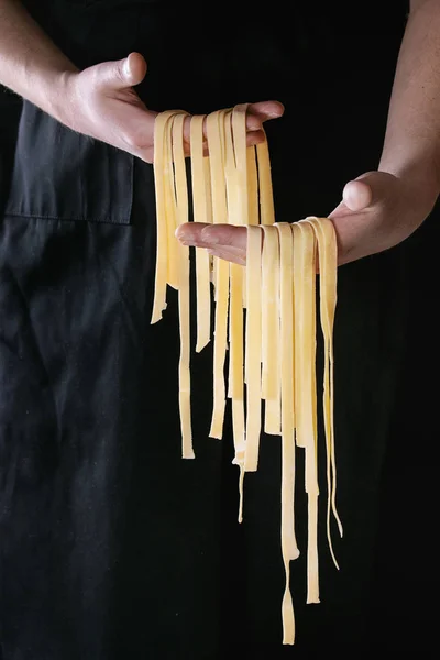 Färsk pasta tagliatelle i mannens händer — Stockfoto