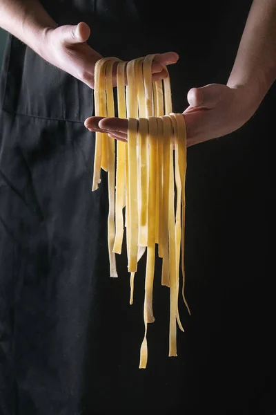 Färsk pasta tagliatelle i mannens händer — Stockfoto