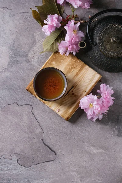 Teekanne und Tasse Tee mit Blütenzweig — Stockfoto