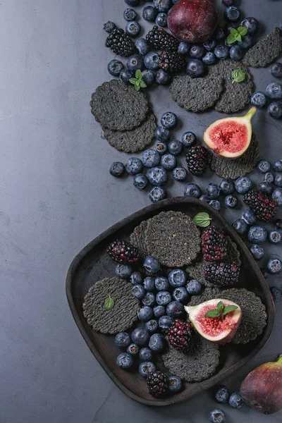 Разнообразие ягод и инжира с черными крекерами — стоковое фото