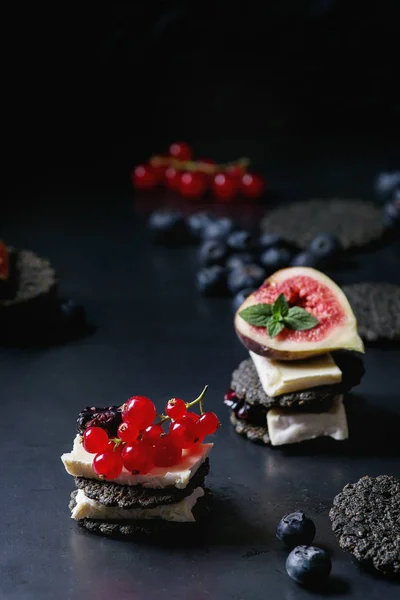 Black crackers with cheese and berries — Stock Photo, Image