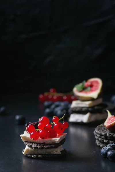 Black crackers with cheese and berries — Stock Photo, Image