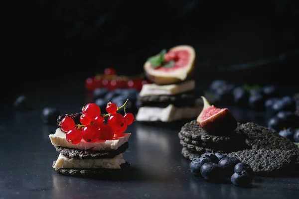 Черные крекеры с сыром и ягодами — стоковое фото