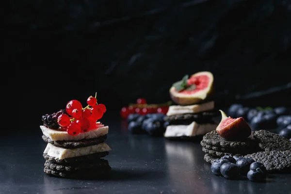 Black crackers with cheese and berries — Stock Photo, Image