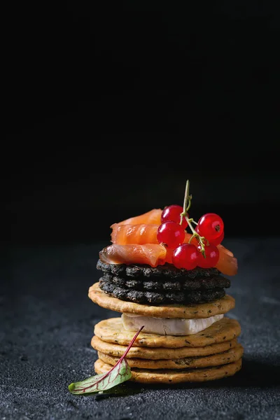 Black crackers with salmon and berries — Stock Photo, Image