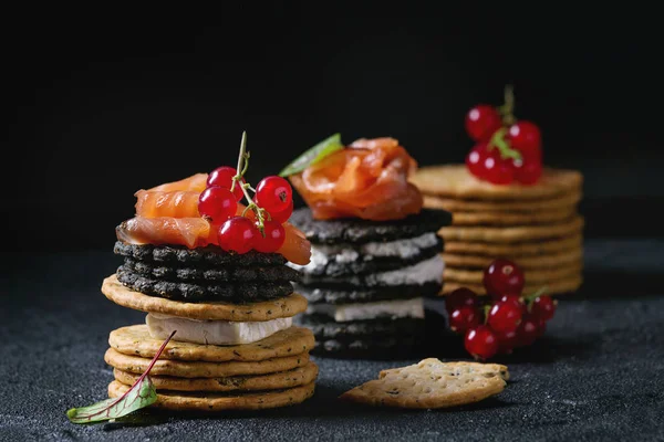 Black crackers with salmon and berries — Stock Photo, Image