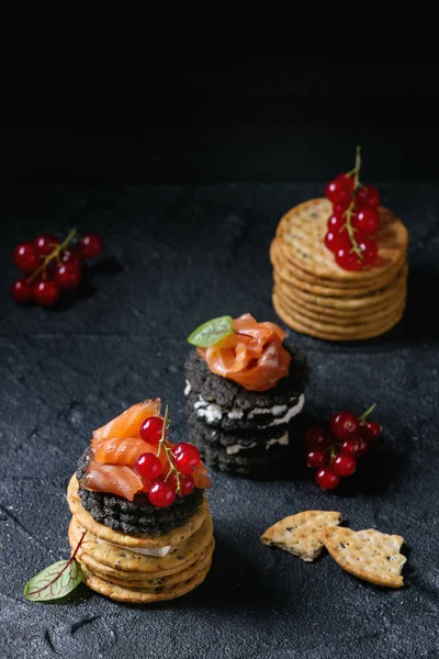 Black crackers with salmon and berries — Stock Photo, Image