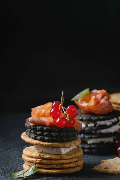 Black crackers with salmon and berries — Stock Photo, Image