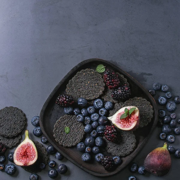 Variety of berries and figs with black crackers — Stock Photo, Image