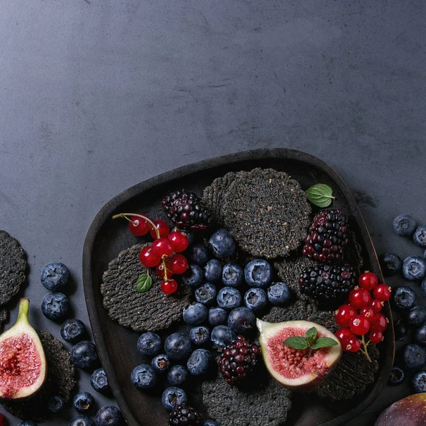 Разнообразие ягод и инжира с черными крекерами — стоковое фото