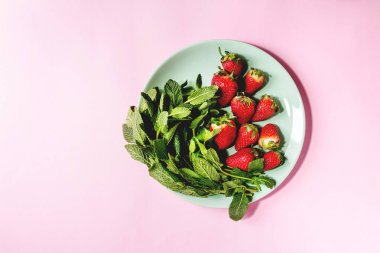 Taze çilek ve demet nane pembe pastel pin-up arka plan üzerinde turkuaz plaka üzerinde. Uzay kopyalayın. Üstten Görünüm