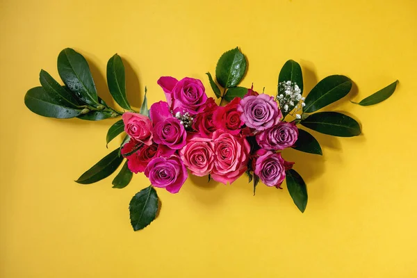 创意布局与美丽的粉红色玫瑰花和绿色叶子在明亮的黄色背景 平躺在床上贺卡概念 — 图库照片
