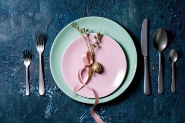 Paskalya sofrası, çatal bıçak takımı, boş tabaklar, söğüt dalları ve altın bıldırcın yumurtası. Klasik mavi doku arka planı. Düz uzanış, boşluk