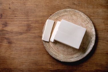 İpek tofu soya peyniri seramik tabakta, ahşap masanın üzerinde çubuklarla. Düz uzanış, boşluk