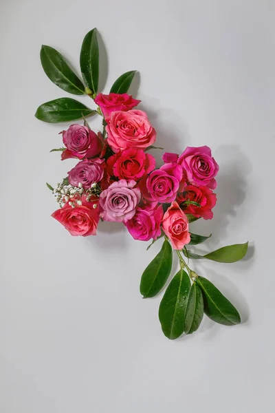 创意布局与美丽的粉红色玫瑰花和绿色叶子灰色背景 平躺在床上贺卡概念 — 图库照片